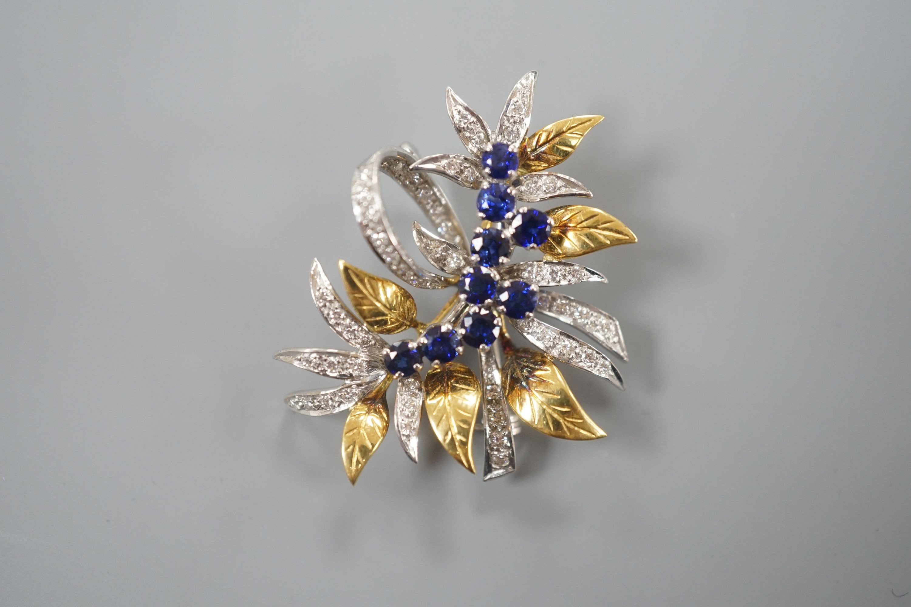 A modern 18ct two colour gold, sapphire and diamond set floral spray brooch, by Cropp & Farr, 38mm, gross weight 11.9 grams.